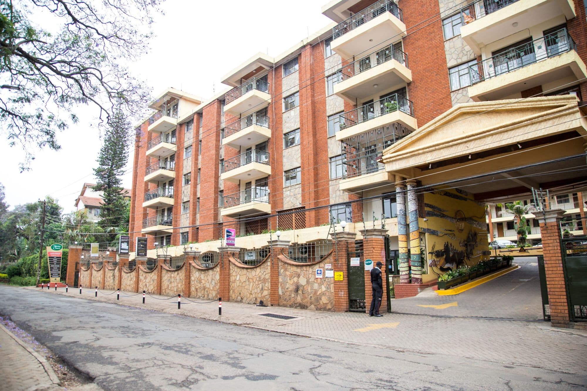 Njema Court's red-brick apartment blocks behind a stone wall on Rhapta Road