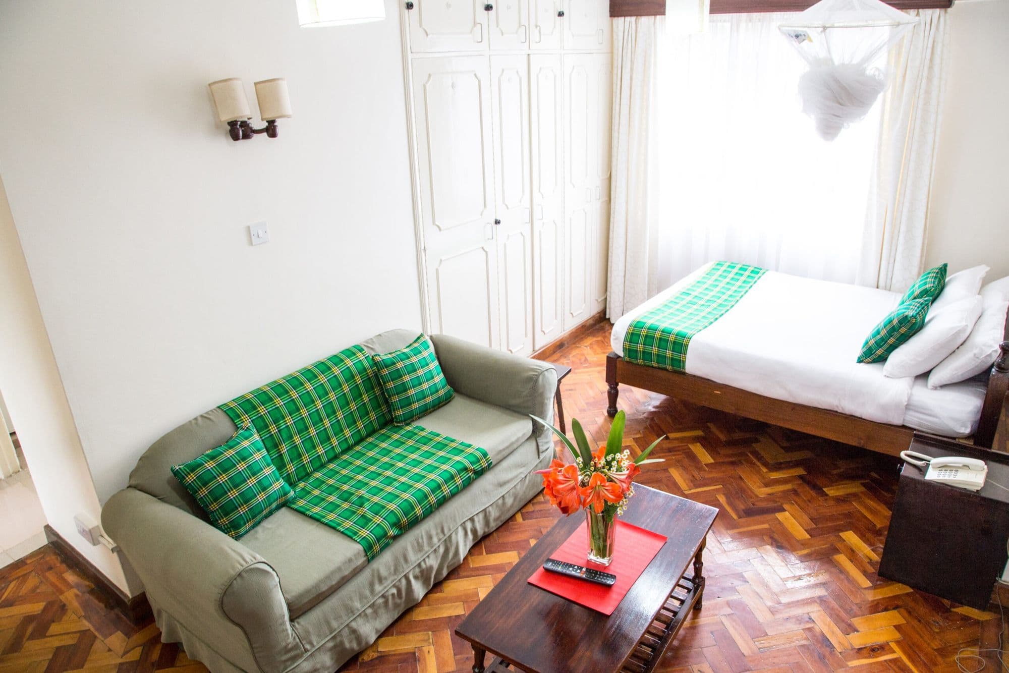 A furnished Njema Court apartment with a green armchair, double bed and parquet floor